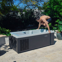 Man interacting with a cold tub in a backyard setting