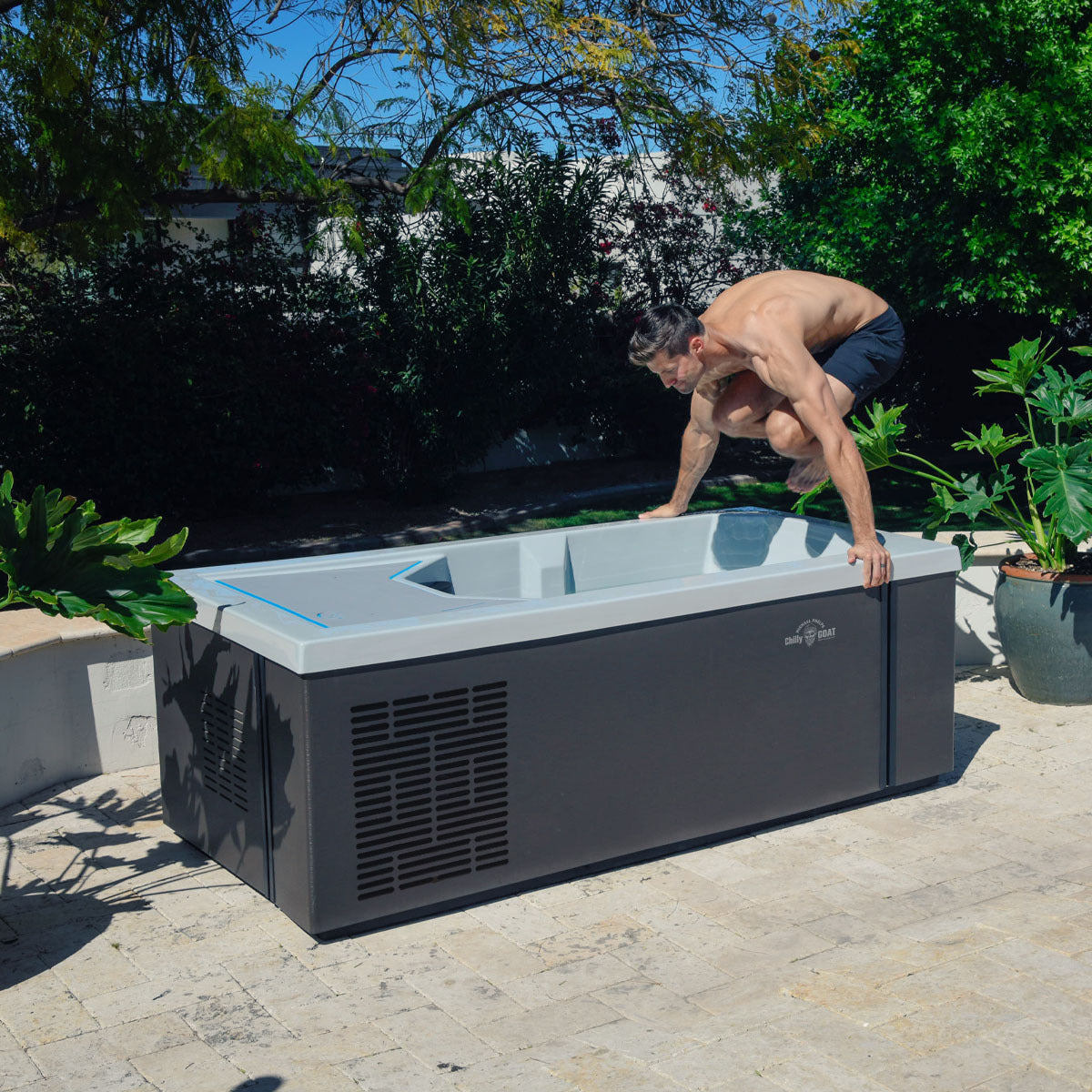 Wooden ice bath with a white interior and cover, placed on a tiled outdoor patio.