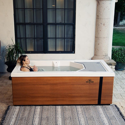 Woman submerged up to chest in cold tub, exhaling